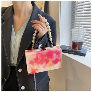 Detail of artistic painted box bag with faux pearl handle and gold metal lock clasp
