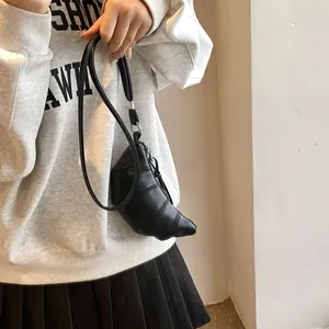 Close-up of black croissant bag featuring minimalist pleats and slim leather strap