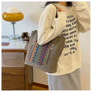 Detail of dark grey canvas tote bag with colorful ethnic embroidery and dual zippers