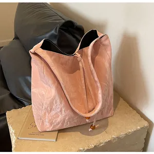 Detalle del bolso tote plisado rosa con correas de cordón y cuentas de madera marrón oscuro