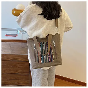Detail view of khaki canvas tote with colorful ethnic embroidery and zipper pockets
