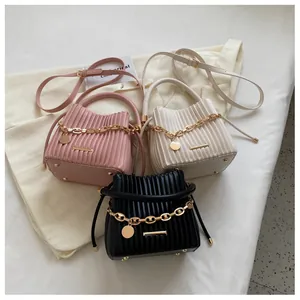 Détail des plis texturés sur les sacs seaux avec chaînes dorées en rose, blanc et noir