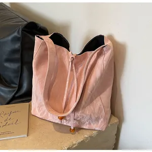 Detalle de bolso tote plisado rosa con cordón de cuentas de ámbar y textura de cuero