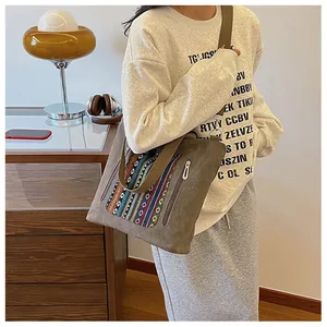 Close-up of ethnic style embroidery and metal zipper detail on brown canvas tote bag