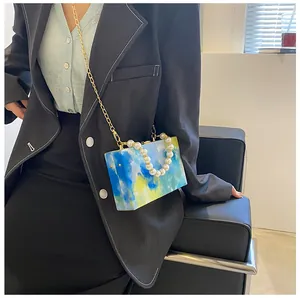Close-up of artistic box bag with blue and yellow oil painting texture and pearl handle