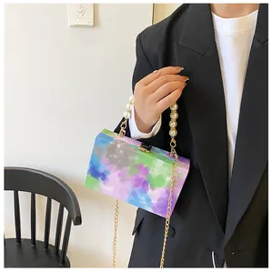 Artistic painted box bag with faux pearl handle and gold chain detail on model