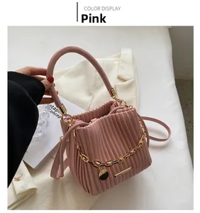 Gros plan du sac seau plissé rose avec chaîne dorée et pendentif en métal circulaire