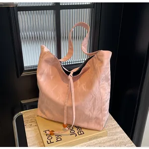 Detalle de bolso tote rosa con tejido de textura plisada y cordón con cuenta ámbar