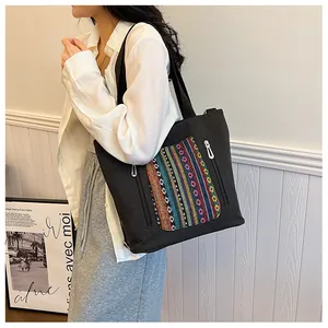 Detailed view of black canvas tote bag featuring colorful ethnic embroidery pocket