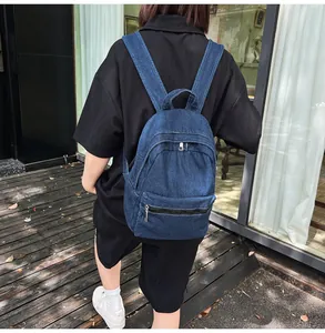 Vista posteriore dettagliata di uno zaino in denim blu con scomparti a cerniera