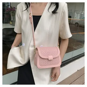 Detail of pink PU leather crossbody bag featuring a woven textured flap and adjustable strap