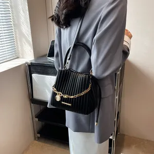 Détail du sac seau plissé noir avec chaîne dorée épaisse et bandoulière en cuir souple