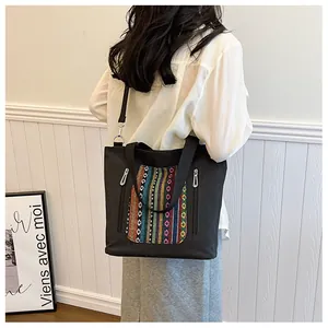 Detail of black canvas tote bag with colorful ethnic embroidery and adjustable strap