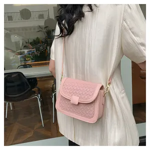 Close-up of pink woven crossbody bag with square buckle and gold metal hardware hooks