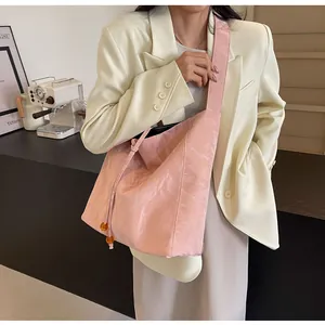 Detalle de bolso plisado rosa con correa ancha y cuentas de ámbar en la modelo