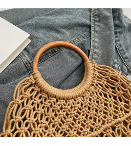Detalle del bolso de paja tejido a mano con asas redondas de madera y diseño de malla