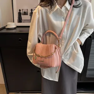 Détail du sac seau plissé rose avec chaîne dorée et finition en similicuir texturé élégant