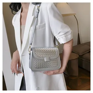 Silver metallic crossbody bag with woven texture worn by model in white suit
