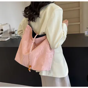Detalle de bolso tote plisado rosa con cordón y cuentas amarillas y diseño espacioso