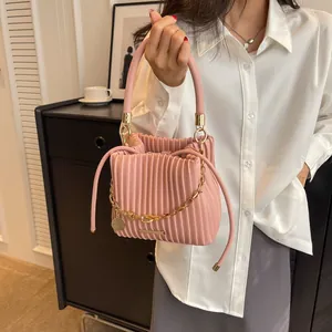 Détail du sac seau rose plissé avec chaîne dorée et finitions à cordon de serrage