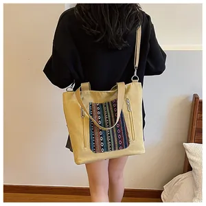 Detail of yellow canvas tote bag featuring ethnic woven pocket and adjustable strap