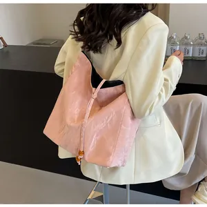 Detalle de bolso tote rosa con textura plisada y cuentas llevado por modelo
