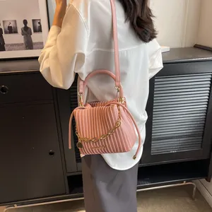 Détail du sac seau plissé rose avec chaîne dorée et texture cuir synthétique fine