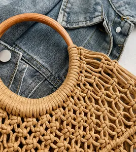 Detalle del bolso de playa tejido a mano con asa de madera redonda y diseño de red floral