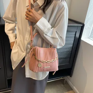 Détail du sac seau plissé rose avec chaîne dorée et texture cuir raffinée