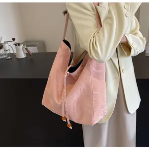 Detalle de bolso tote plisado rosa con cordón y cuentas de color ámbar