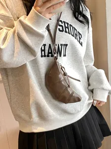 Brown mini leather croissant bag necklace style with adjustable thin strap and zipper detail