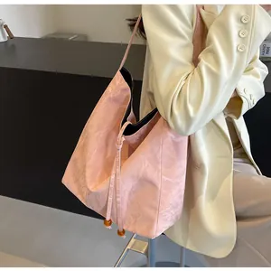 Detalle del bolso rosa con textura de nube y cierre de cordón con cuentas marrones