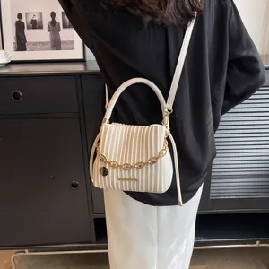 Détail du sac seau plissé blanc avec chaîne dorée décorative et pendentif circulaire élégant