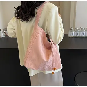 Textura detallada de un bolso tote rosa plisado con cuenta de ámbar y lateral fruncido