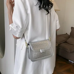 Silver metallic crossbody bag with woven texture worn by model over white top