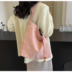 Primer plano de bolso tote plisado rosa con cordón ajustable y cuentas de ámbar