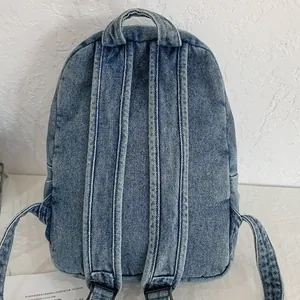 Vista posteriore di uno zaino in denim lavato blu con spallacci regolabili e manico alto