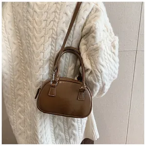 Détail d'un petit sac Boston marron vintage en cuir brillant avec poignées rondes