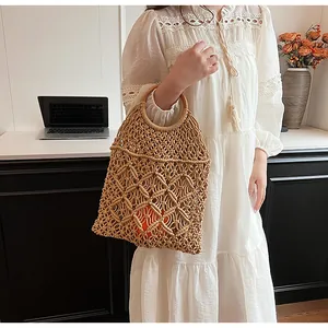 Detalle del bolso de paja trenzada con asas redondas de madera y diseño calado