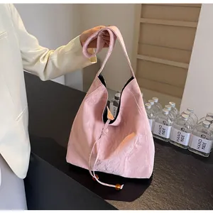Detalle de bolso plisado rosa con cierre de cordón y adornos de cuentas ámbar