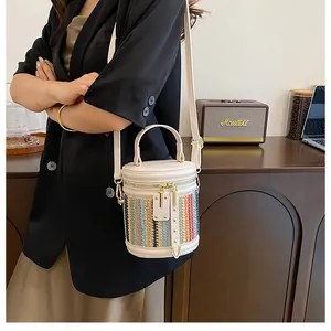 Detailed view of a multi-colored woven straw crossbody bag with beige leather trim and strap