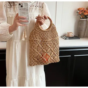 Detalle de la bolsa de paja tejida a mano con asas redondas de madera y forro naranja cálido