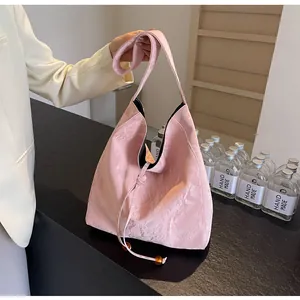 Detalle de bolso hobo rosa pálido con textura plisada y cordón con cuentas de ámbar