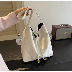Detalle del bolso hobo con cordón y cuentas de ámbar sobre cuero sintético color crema