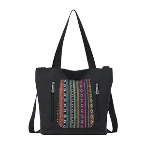 Black canvas tote bag with colorful ethnic embroidery and vertical dual zipper pockets