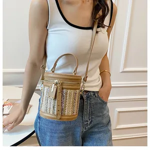 Detailed shot of straw bucket bag with contrast leather stitching and gold rivet details