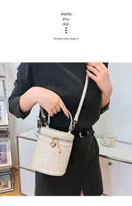 Détail du sac seau tressé beige avec élégant pendentif doré en forme de cœur au zip