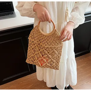 Detalle del bolso tote bohemio de punto calado con asas redondas de madera y forro naranja