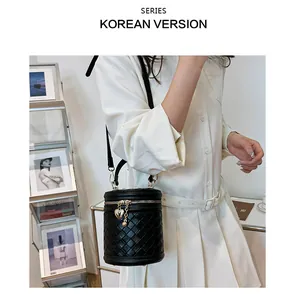 Détail du sac seau noir tressé avec pendentif cœur et bandoulière réglable