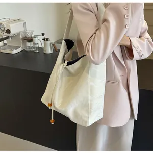 Detalle del bolso tote blanco roto con textura plisada y cuentas de ámbar en una cafetería